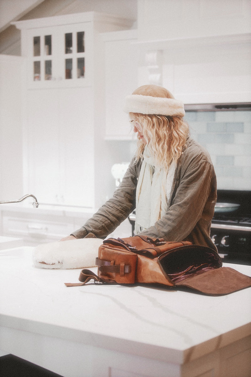 Person sitting at a kitchen counter with a brown leather bag on the counter
